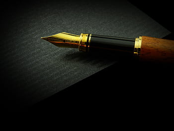 Detailed close-up of a classic fountain pen nib on textured black paper, showcasing elegance. HD wallpaper