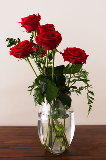 Beautiful bouquet of red roses in a clear glass vase on a wooden surface. HD phone wallpaper