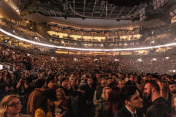 A large crowd gathers in an indoor arena for a lively event, surrounded by bright lights. HD wallpaper