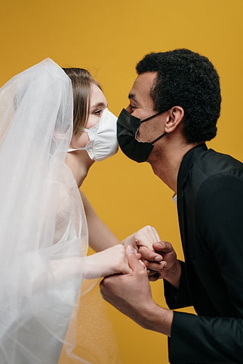 Bride and groom kissing with masks, illustrating pandemic love and protection. HD phone wallpaper