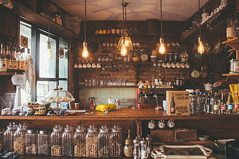 A cozy cafe with rustic decor, pendant lights, and glass jars creates a vintage ambiance. HD wallpaper