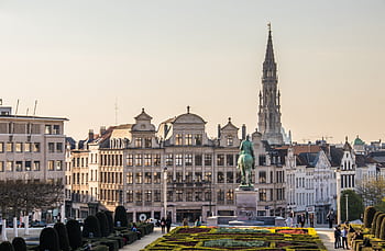 A beautiful cityscape of Brussels with the iconic Town Hall tower and vibrant gardens. HD wallpaper