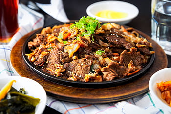 Delicious Korean BBQ beef dish with vegetables and sesame sprinkled on a hot plate. HD wallpaper