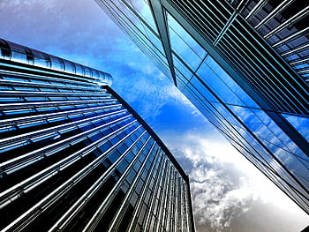 Low angle view of modern skyscrapers with reflective glass against a bright blue sky. HD wallpaper