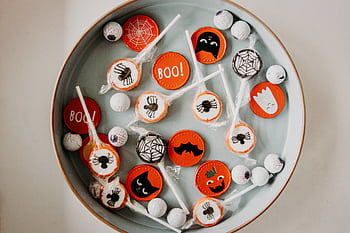 A vibrant assortment of Halloween-themed candies in a bowl, perfect for seasonal celebrations. HD wallpaper
