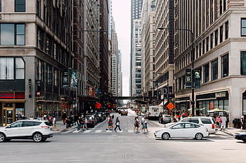 Dynamic cityscape showcasing pedestrians walking among skyscrapers and vehicles. HD wallpaper