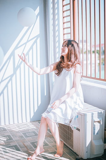 A young woman in a white dress enjoying playful sunlight indoors. HD phone wallpaper