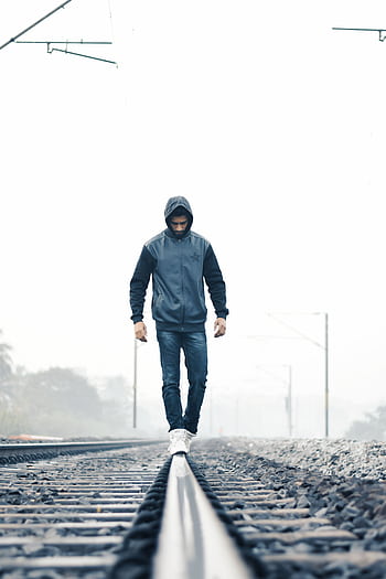 A man in winter clothes walking on train tracks amidst foggy weather, symbolizing solitude. HD phone wallpaper