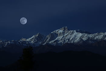 Stunning view of snow-capped mountains illuminated by a full moon under a clear night sky. HD wallpaper