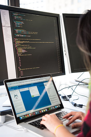 Programmer working on code across multiple screens in a modern office setting. HD phone wallpaper