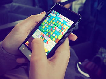 Hands holding a smart with a colorful puzzle game on the screen, displaying modern technology. HD wallpaper