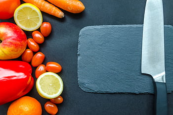 Vibrant fruits and vegetables with a stainless steel knife on slate, perfect for healthy eating concepts. HD wallpaper