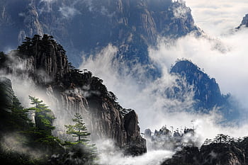 Misty mountain peaks of Huangshan, China enveloped in fog, creating a serene and dramatic landscape. HD wallpaper