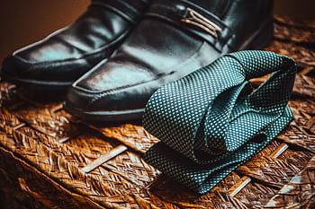 Close-up of a stylish necktie and polished leather shoes resting on a woven wicker surface. HD wallpaper