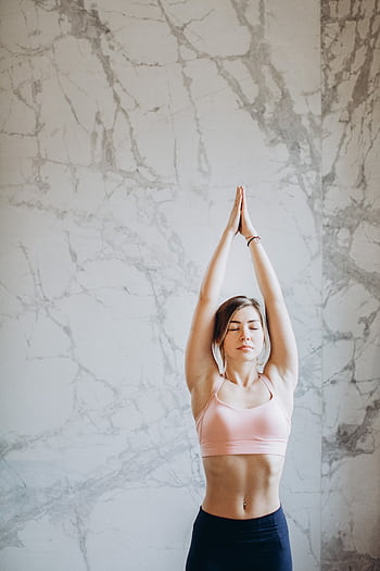 Young woman performing upward salute yoga pose indoors with marble background. HD phone wallpaper