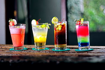 Colorful assortment of cocktails on a rustic wooden table, perfect for a refreshing summer evening. HD wallpaper