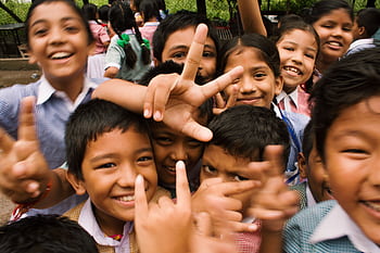 A joyful group of children smiling and making playful gestures outdoors in Namarjung, Nepal. HD wallpaper