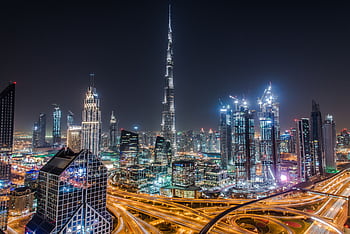 A stunning view of Dubai's illuminated skyline featuring the towering Burj Khalifa at night. HD wallpaper