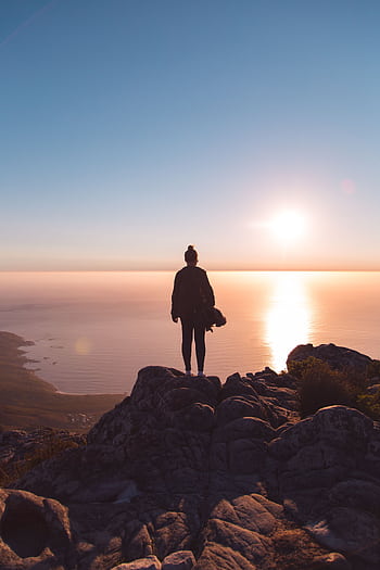Silhouette of a person standing on a rocky cliff, enjoying the stunning sunset over the ocean in Cape Town. HD phone wallpaper