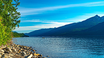Green Trees Stones Lake Boat Coast Greenery Mountains Under White Clouds Blue Sky During Daytime Nature HD wallpaper