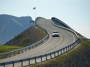 A car driving on the iconic Atlantic Ocean Road with coastal views and winding architecture. HD wallpaper