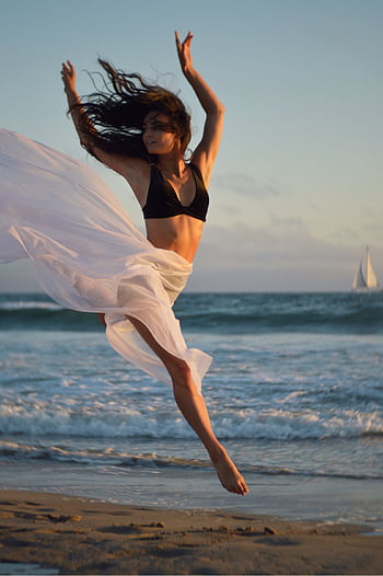 A graceful ballerina leaps barefoot on a sunlit beach by the ocean. HD phone wallpaper