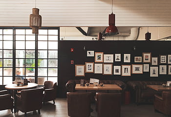 Cozy café interior featuring leather chairs, framed wall art, and pendant lighting. Ideal for meetings. HD wallpaper