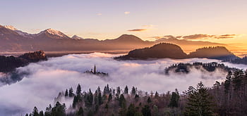 Majestic sunrise over misty mountains and forest, creating a serene landscape. HD wallpaper