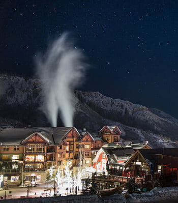 Charming winter night scene in Snowmass Village with snow-covered buildings under a starry sky. HD phone wallpaper