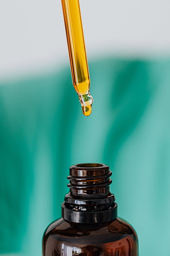 Detailed view of an amber glass bottle and dropper used in laboratory or medical setting, illustrating chemical experimentation. HD phone wallpaper