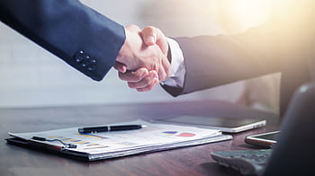 Professional handshake agreement over business charts in an office setting. HD wallpaper