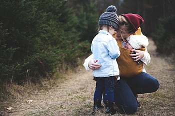 A loving mother with her two children exploring a forest path during the day. HD wallpaper