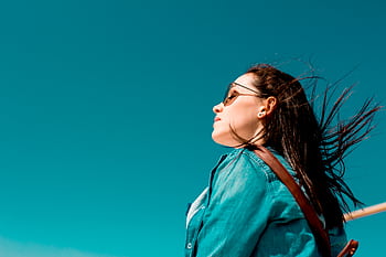 Fashionable woman outdoors in denim shirt with sunglasses under clear blue sky, enjoying sunny weather. HD wallpaper