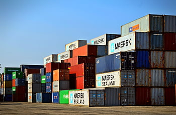 Colorful stacked shipping containers at a port exemplify global logistics. HD wallpaper
