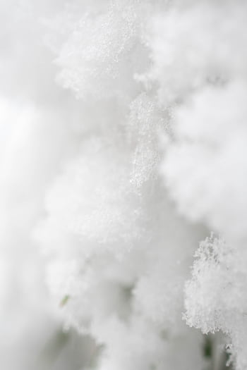 A detailed close-up of fresh, soft snow showcasing fine textures and frost in winter light. HD phone wallpaper
