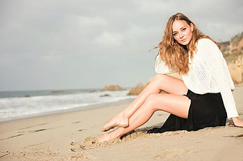 LAURA BILGERI, white knit top, red hair, sitting on the beach, sea, sand, black skirt HD wallpaper