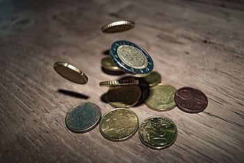 Capture of euro coins falling and spinning on a wooden table. Perfect depiction of finance and currency.