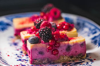 Sliced berry cheesecake topped with vibrant fresh berries and served on a decorative plate. HD wallpaper