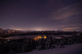 Starry night with snow-covered trees and mountains in the French Alps at Viuz-la-Chiésaz. HD wallpaper