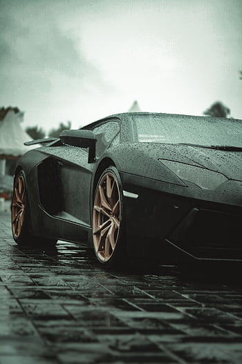 Close-up of a Lamborghini Aventador parked on a rainy street, showcasing its elegance and design. HD phone wallpaper