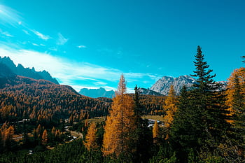 Capture the essence of fall with this vibrant mountain landscape showcasing autumn colors and blue skies. HD wallpaper