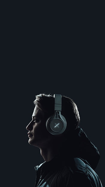 Moody portrait of a young man wearing heads against a dark studio backdrop. HD phone wallpaper