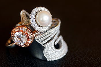 Close-up of luxurious pearl and diamond rings with gold accents on a black background. HD wallpaper