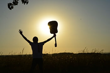 A young guitarist celebrates the sunrise with an acoustic guitar, creating a dramatic silhouette. HD wallpaper