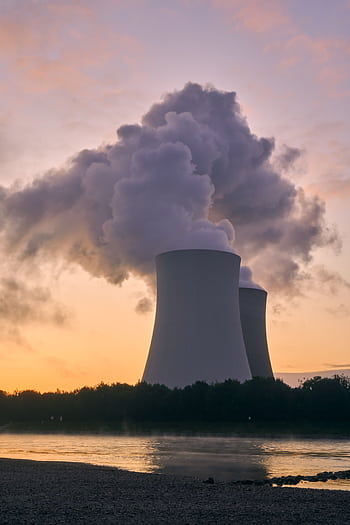 Silhouette of a nuclear power plant emitting steam during a colorful sunset. HD phone wallpaper