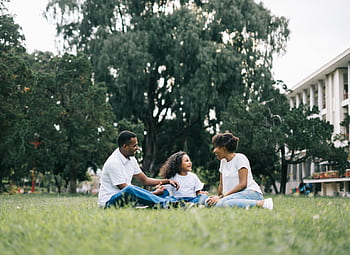 A happy black family enjoying quality time together outdoors in a lush green park. HD wallpaper