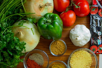 An assortment of fresh vegetables and spices on a wooden table for healthy cooking. HD wallpaper