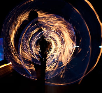 Mesmerizing long exposure shot of fire spinning and silhouette at night. HD wallpaper