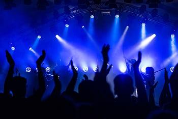 Dynamic concert scene with cheering crowd and vibrant blue lighting. HD wallpaper
