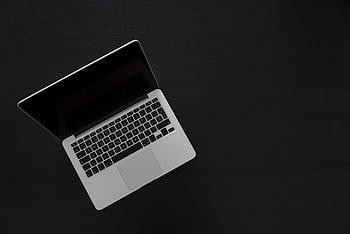 Overhead view of a MacBook laptop on a dark desk, showcasing modern technology and minimalism. HD wallpaper